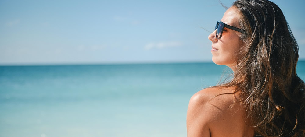 Persona usando gafas de sol con protección UV en la playa